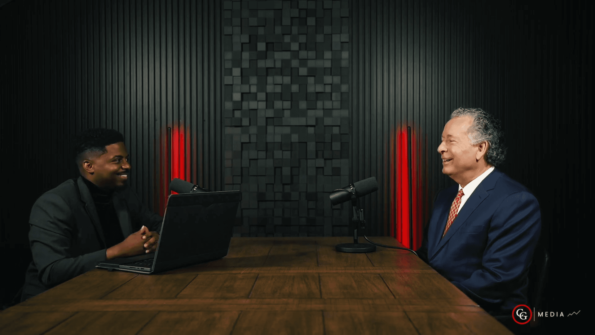 Host Elvis Casely interviewing trial lawyer Randy Calvert during an episode of 60 Minutes: Inside Trial Minds, seated across from each other in a studio with microphones.